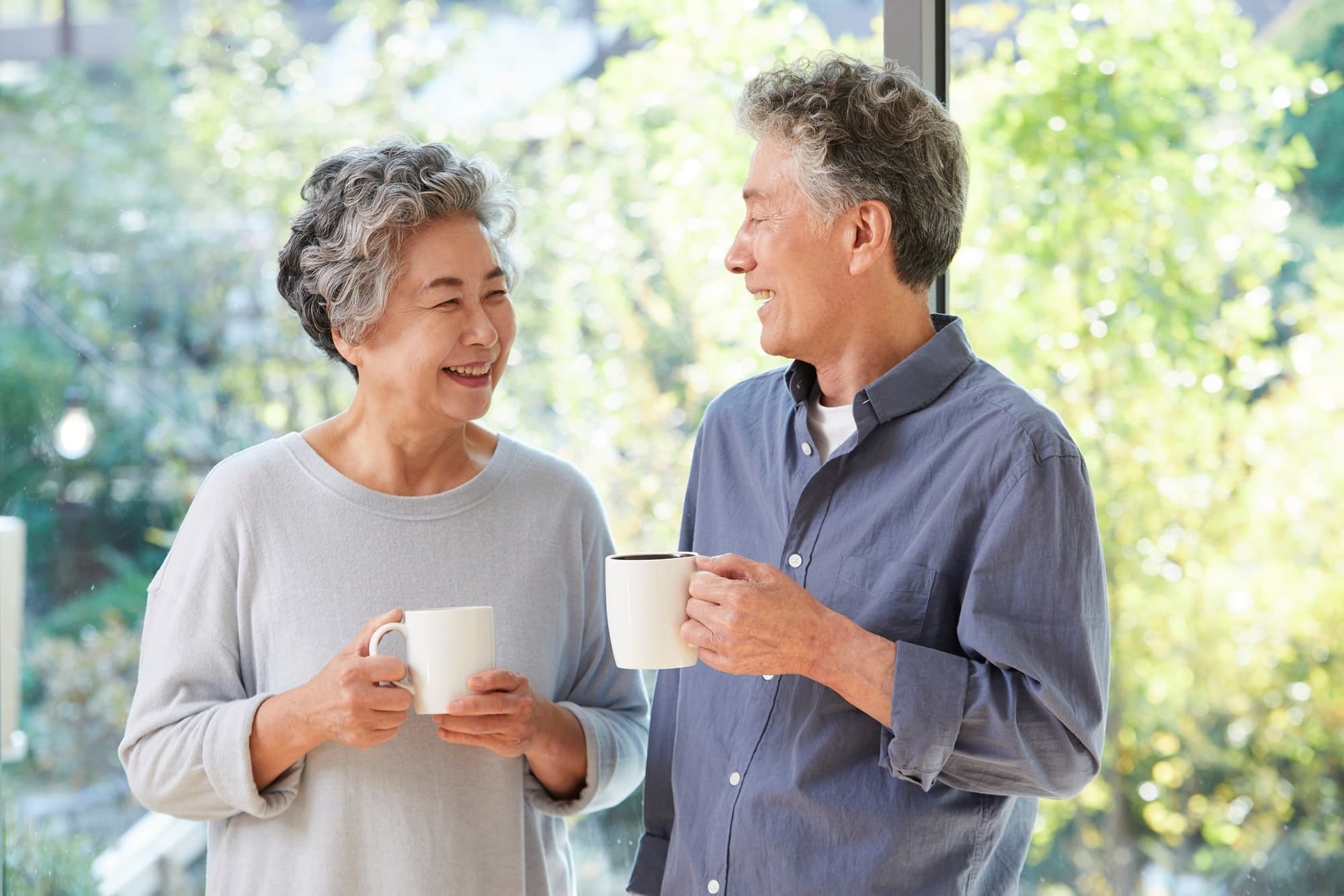 マグカップを持って微笑み合うシニア夫婦