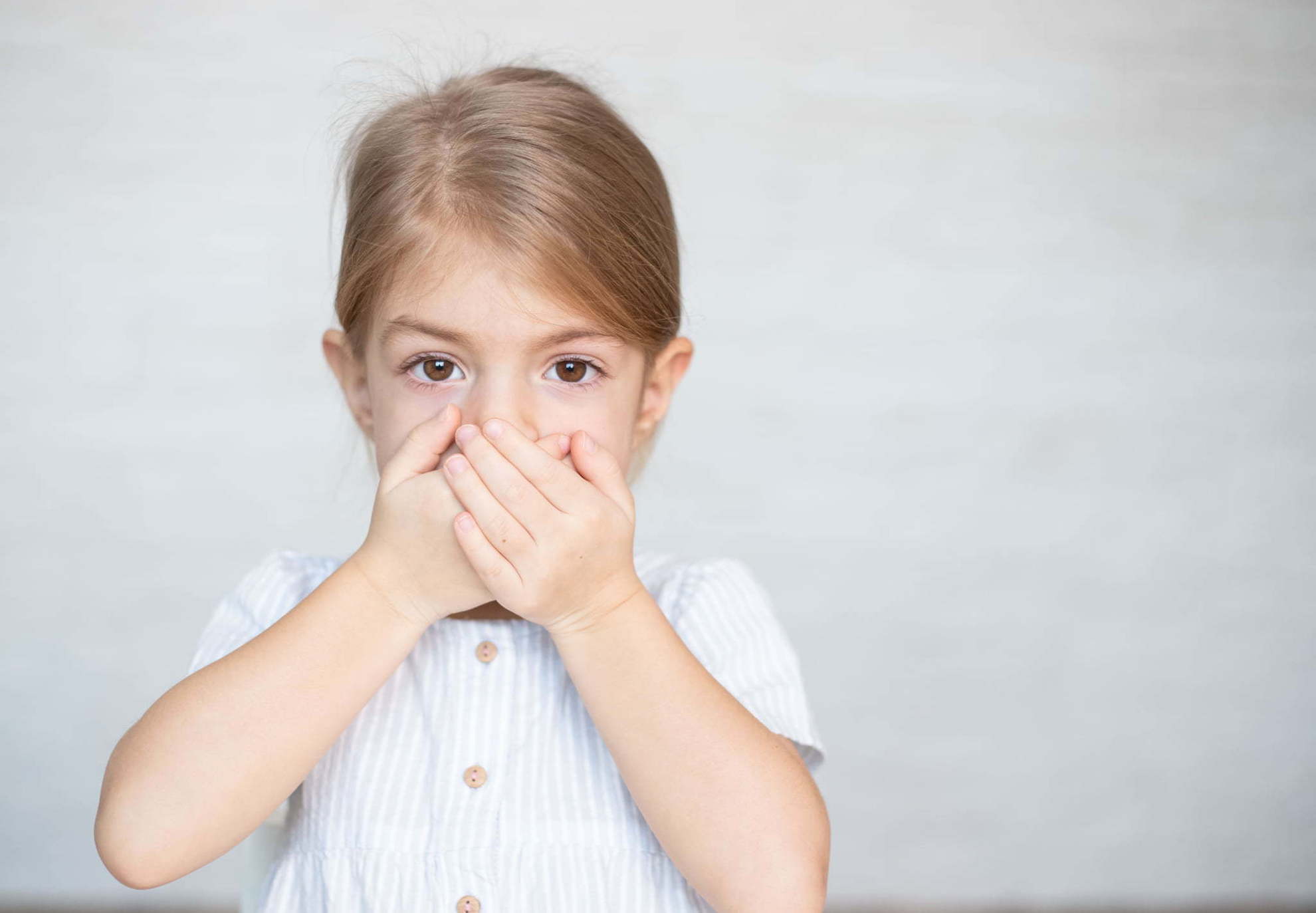 八重歯にコンプレックスを感じて手で口をふさぐ子ども